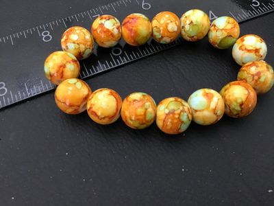 Sale Photo Thumbnail #48: Beaded stretch bracelet featuring round beads in mottled, marbled shades of orange, yellow, and mint green. Each bead measures approximately 8mm to 10mm in diameter. Shows light wear and is in good pre-owned condition.
