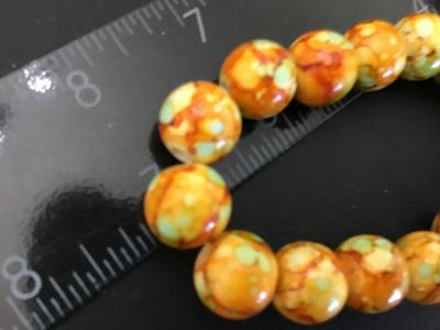 Sale Photo Thumbnail #50: Beaded stretch bracelet featuring round beads in mottled, marbled shades of orange, yellow, and mint green. Each bead measures approximately 8mm to 10mm in diameter. Shows light wear and is in good pre-owned condition.