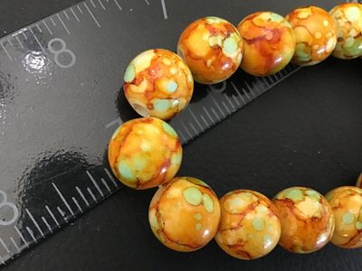 Sale Photo Thumbnail #49: Beaded stretch bracelet featuring round beads in mottled, marbled shades of orange, yellow, and mint green. Each bead measures approximately 8mm to 10mm in diameter. Shows light wear and is in good pre-owned condition.