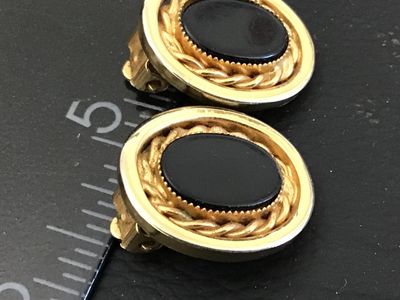 Sale Photo Thumbnail #52: Pair of vintage oval clip-on earrings featuring black oval cabochons set within a twisted rope accent border and smooth gold-tone bezel. Each earring measures approximately 1 inch in height. Clip-on backs are functional. Good vintage condition with minor 