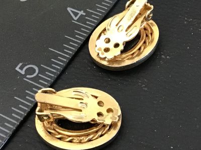 Sale Photo Thumbnail #53: Pair of vintage oval clip-on earrings featuring black oval cabochons set within a twisted rope accent border and smooth gold-tone bezel. Each earring measures approximately 1 inch in height. Clip-on backs are functional. Good vintage condition with minor 