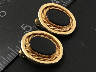 Sale Photo Thumbnail #51: Pair of vintage oval clip-on earrings featuring black oval cabochons set within a twisted rope accent border and smooth gold-tone bezel. Each earring measures approximately 1 inch in height. Clip-on backs are functional. Good vintage condition with minor 