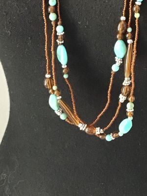 Sale Photo Thumbnail #56: Multi-strand layered necklace featuring turquoise-colored focal beads, amber-tone glass or acrylic spacer beads, silver-tone accent spacers, and brown seed bead strands. Good pre-owned condition with no visible damage or broken strands.