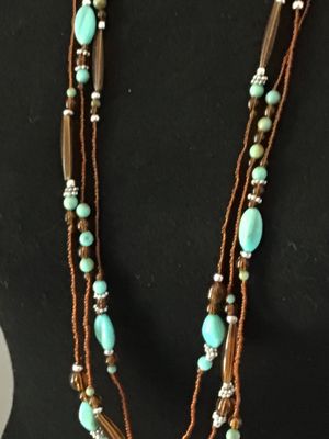 Sale Photo Thumbnail #54: Multi-strand layered necklace featuring turquoise-colored focal beads, amber-tone glass or acrylic spacer beads, silver-tone accent spacers, and brown seed bead strands. Good pre-owned condition with no visible damage or broken strands.