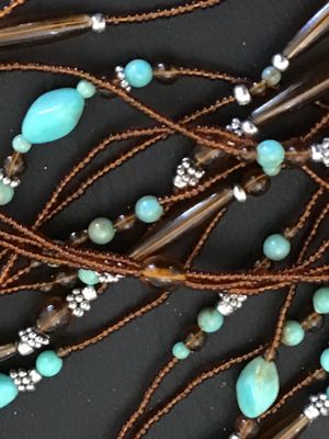 Sale Photo Thumbnail #55: Multi-strand layered necklace featuring turquoise-colored focal beads, amber-tone glass or acrylic spacer beads, silver-tone accent spacers, and brown seed bead strands. Good pre-owned condition with no visible damage or broken strands.