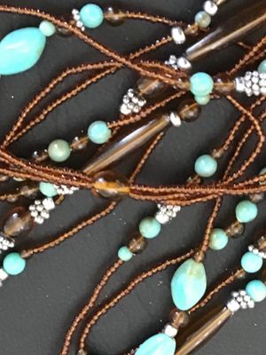 Sale Photo Thumbnail #58: Multi-strand layered necklace featuring turquoise-colored focal beads, amber-tone glass or acrylic spacer beads, silver-tone accent spacers, and brown seed bead strands. Good pre-owned condition with no visible damage or broken strands.