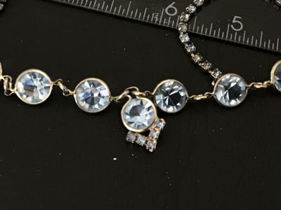 Sale Photo Thumbnail #61: Vintage silver-tone choker necklace featuring bezel-set round light blue glass rhinestones and a central drop pendant with additional small rhinestone accents. Measures approximately 14-15 inches in length. Secured with a fold-over clasp. Good vintage con