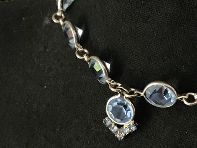 Sale Photo Thumbnail #60: Vintage silver-tone choker necklace featuring bezel-set round light blue glass rhinestones and a central drop pendant with additional small rhinestone accents. Measures approximately 14-15 inches in length. Secured with a fold-over clasp. Good vintage con