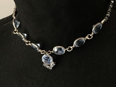 Sale Photo Thumbnail #62: Vintage silver-tone choker necklace featuring bezel-set round light blue glass rhinestones and a central drop pendant with additional small rhinestone accents. Measures approximately 14-15 inches in length. Secured with a fold-over clasp. Good vintage con