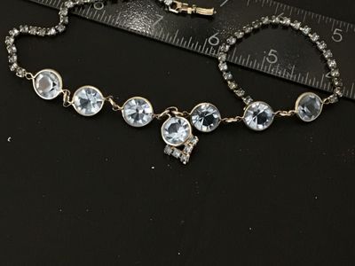 Sale Photo Thumbnail #59: Vintage silver-tone choker necklace featuring bezel-set round light blue glass rhinestones and a central drop pendant with additional small rhinestone accents. Measures approximately 14-15 inches in length. Secured with a fold-over clasp. Good vintage con