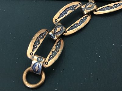 Sale Photo Thumbnail #80: Vintage copper link bracelet featuring stamped geometric designs with black enamel or niello accent fill. Features open cut-out oval links connected by decorative connector bars and a hook/ring clasp. Measures approximately 7 to 7.5 inches in length. Show