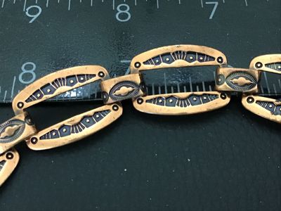 Sale Photo Thumbnail #77: Vintage copper link bracelet featuring stamped geometric designs with black enamel or niello accent fill. Features open cut-out oval links connected by decorative connector bars and a hook/ring clasp. Measures approximately 7 to 7.5 inches in length. Show