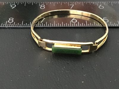 Sale Photo Thumbnail #93: Vintage gold-tone hinged cuff/bangle bracelet featuring a rectangular green glass or faux jade centerpiece. Marked '© AVON' on the back of the center setting. Measures approximately 2.5 inches in inner width. Good vintage condition with light wear consis