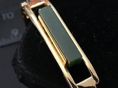 Sale Photo Thumbnail #95: Vintage gold-tone hinged cuff/bangle bracelet featuring a rectangular green glass or faux jade centerpiece. Marked '© AVON' on the back of the center setting. Measures approximately 2.5 inches in inner width. Good vintage condition with light wear consis