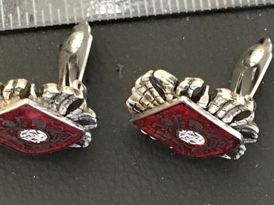 Sale Photo Thumbnail #101: Pair of vintage clip-on earrings featuring a textured silver-tone crown motif surrounding a diamond-shaped red enamel panel. The central shield showcases a detailed coat of arms/heraldic crest design. Silver-tone textured backs with functional clip closur