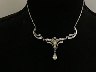 Sale Photo Thumbnail #109: A vintage silver-tone festoon style necklace featuring filigree-style openwork links, accented with clear round and marquise-cut rhinestones and a dangling teardrop rhinestone centerpiece. The center feature measures approximately 3 inches across, and the