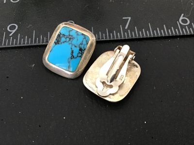 Sale Photo Thumbnail #112: Pair of vintage clip-on earrings featuring bezel-set rectangular turquoise stones with fine dark matrix. Crafting in sterling silver, stamped '925' on the clip findings. Each earring measures approximately 3/4 inch long. In good pre-owned condition with s