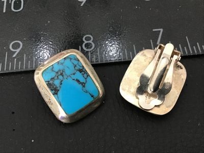 Sale Photo Thumbnail #111: Pair of vintage clip-on earrings featuring bezel-set rectangular turquoise stones with fine dark matrix. Crafting in sterling silver, stamped '925' on the clip findings. Each earring measures approximately 3/4 inch long. In good pre-owned condition with s
