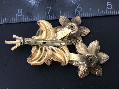 Sale Photo Thumbnail #115: Vintage gold-tone brooch featuring a floral bouquet design set with colorful round rhinestones in red, aqua blue, and amber yellow. The back features a standard pin bar closure. Measures approximately 3 inches in length. Shows vintage wear including patin