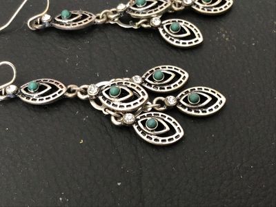 Sale Photo Thumbnail #122: Pair of ornate silver-tone chandelier drop earrings featuring marquee-shaped filigree elements, small turquoise-colored cabochons, and clear crystal accents. Wire fishhook ear wires. Measure approximately 2.5 inches in length. In good condition with light