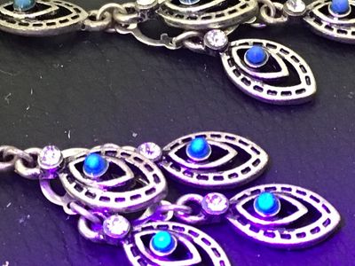 Sale Photo Thumbnail #121: Pair of ornate silver-tone chandelier drop earrings featuring marquee-shaped filigree elements, small turquoise-colored cabochons, and clear crystal accents. Wire fishhook ear wires. Measure approximately 2.5 inches in length. In good condition with light