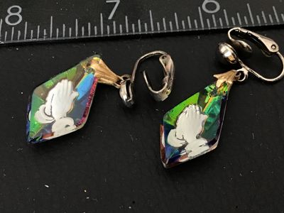 Sale Photo Thumbnail #125: Pair of vintage clip-on dangle earrings featuring iridescent aurora borealis (AB) glass or crystal drop pendants. Each crystal is diamond-shaped with an Intaglio-style molded or etched praying hands design highlighted in white on the front and silver foil