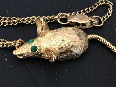 Sale Photo Thumbnail #128: Vintage gold-tone chain necklace featuring a textured mouse pendant with green rhinestone eyes and a flexible snake chain tail. The pendant has a brushed finish detail. Includes a fold-over or spring clasp mechanism. Good vintage condition with light, sta