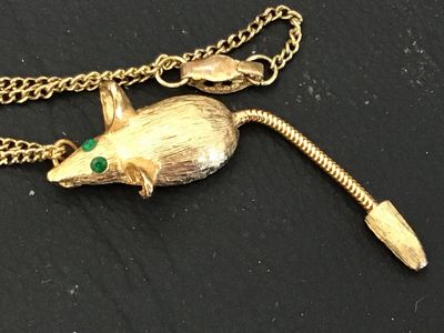Sale Photo Thumbnail #127: Vintage gold-tone chain necklace featuring a textured mouse pendant with green rhinestone eyes and a flexible snake chain tail. The pendant has a brushed finish detail. Includes a fold-over or spring clasp mechanism. Good vintage condition with light, sta