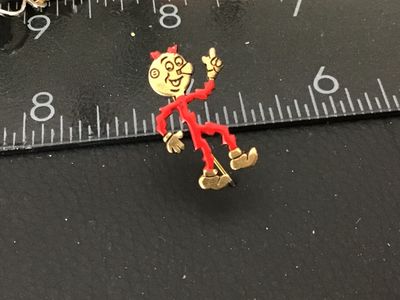 Sale Photo Thumbnail #132: Small lot of vintage items including an advertising lapel pin featuring Reddy Kilowatt, marked on the back with REDDY KILOWATT and a registered trademark symbol, measuring under 1 inch tall. Also includes a silver-tone filigree necklace featuring clear rh