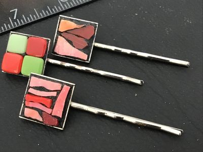 Sale Photo Thumbnail #135: A lot of three decorative silver-tone hair bobby pins featuring square mosaic and enamel tile tops. Includes one featuring green and red grid tiles and two featuring mosaic glass in shades of pink, red, and coral set in dark grout. Each pin measures appro