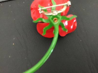 Sale Photo Thumbnail #139: Vintage bright red enamel rose brooch with a long green stem and leaf detailing underneath. Features a standard pin back with rollover safety clasp. Measures approximately 3 inches in length. In good vintage condition with minor wear to the finish consist