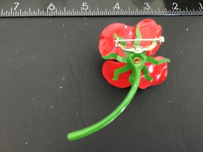 Sale Photo Thumbnail #140: Vintage bright red enamel rose brooch with a long green stem and leaf detailing underneath. Features a standard pin back with rollover safety clasp. Measures approximately 3 inches in length. In good vintage condition with minor wear to the finish consist