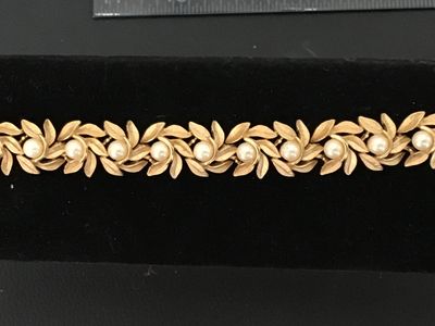 Sale Photo Thumbnail #2: Vintage costume jewelry bracelet featuring brushed textured gold tone leaf links accented with round faux pearls throughout. Includes a fold-over clasp. Good vintage condition with light, age-appropriate wear.