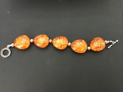 Sale Photo Thumbnail #7: Faux amber chunk bead statement bracelet featuring five large orange translucent, multi-faceted faux amber stones interspersed with textured silver-tone metal spacer beads. Finished with a decorative silver-tone toggle closure. Good condition with light s