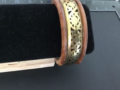 Sale Photo Thumbnail #16: A vintage bangle bracelet crafted from natural wood with an inset center band of openwork brass filigree. Shows light pre-owned wear consistent with age. Measures approximately 3 inches in outer diameter.