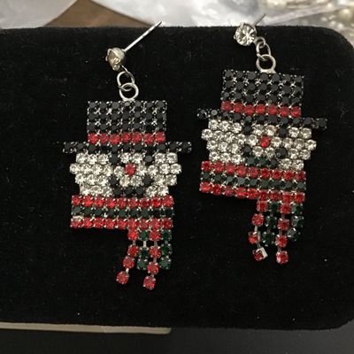 Sale Photo Thumbnail #47: Pair of festive holiday dangle earrings featuring a detailed snowman design crafted from clear, black, red, and green rhinestones set in silver-tone metal. Earrings feature post-back closures and articulated fringe scarves. Appears in good condition with 
