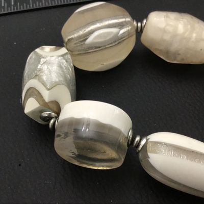 Sale Photo Thumbnail #54: A statement stretch bracelet featuring large, chunky art glass beads in opaque white, clear glass, and foil-lined accents. The beads come in various shapes including oval, round disc, and barrel forms, separated by small silvertone spacer beads. Good cond