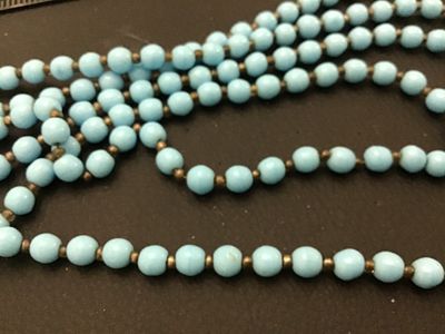 Sale Photo Thumbnail #76: Vintage multi-strand long necklace featuring light blue round beads separated by small dark spacer beads. Includes a gold-tone filigree push-in box clasp. Good vintage condition with light wear consistent with age.