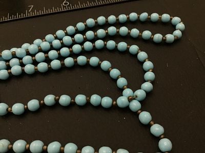 Sale Photo Thumbnail #74: Vintage multi-strand long necklace featuring light blue round beads separated by small dark spacer beads. Includes a gold-tone filigree push-in box clasp. Good vintage condition with light wear consistent with age.