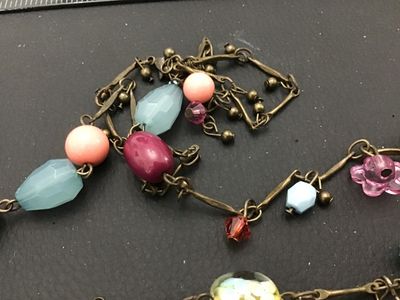 Sale Photo Thumbnail #82: Long brass-tone chain station necklace featuring a mix of colorful glass and acrylic beads, including floral charms, lampwork-style floral glass beads, faceted light blue drops, and pink cabochons. Good pre-owned condition with no visible damage.