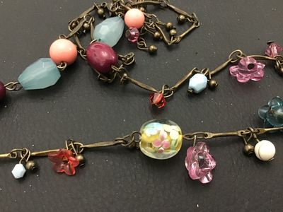 Sale Photo Thumbnail #77: Long brass-tone chain station necklace featuring a mix of colorful glass and acrylic beads, including floral charms, lampwork-style floral glass beads, faceted light blue drops, and pink cabochons. Good pre-owned condition with no visible damage.