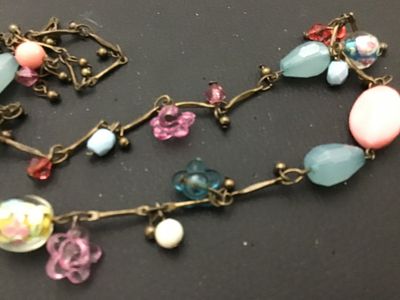 Sale Photo Thumbnail #78: Long brass-tone chain station necklace featuring a mix of colorful glass and acrylic beads, including floral charms, lampwork-style floral glass beads, faceted light blue drops, and pink cabochons. Good pre-owned condition with no visible damage.