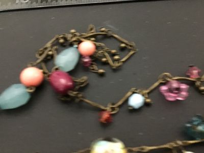 Sale Photo Thumbnail #79: Long brass-tone chain station necklace featuring a mix of colorful glass and acrylic beads, including floral charms, lampwork-style floral glass beads, faceted light blue drops, and pink cabochons. Good pre-owned condition with no visible damage.