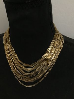 Sale Photo Thumbnail #83: A striking vintage multi-strand statement necklace featuring tiered rows of gold-tone bar-shaped links. Designed with a hook-and-tail clasp featuring a decorative sphere end cap. The necklace shows light wear consistent with age, with all strands intact a