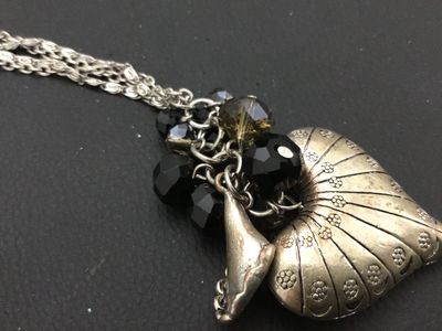 Sale Photo Thumbnail #92: Long silver-tone double-chain necklace featuring a detailed textured nautilus shell pendant clustered with faceted black and smoky glass beads. Good condition with light minor surface wear to the finish.