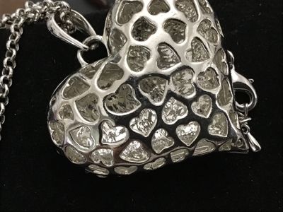Sale Photo Thumbnail #102: A silver-tone chain necklace featuring a large heart-shaped pendant encrusted with clear and aurora borealis pave rhinestones. The back of the pendant features a openwork filigree heart pattern. Features an adjustable rolo chain with a lobster claw clasp.