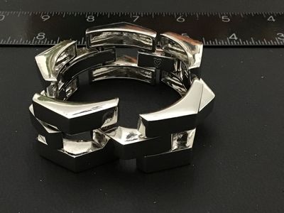 Sale Photo Thumbnail #126: Bold modern silver-tone wide link bracelet featuring stylized chevron/peak top panels with textured open undersides and a fold-over clasp. Features a small heart symbol stamped near the clasp. Bracelet measures approximately 7.5 to 8 inches in length and 