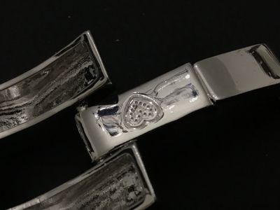 Sale Photo Thumbnail #125: Bold modern silver-tone wide link bracelet featuring stylized chevron/peak top panels with textured open undersides and a fold-over clasp. Features a small heart symbol stamped near the clasp. Bracelet measures approximately 7.5 to 8 inches in length and 
