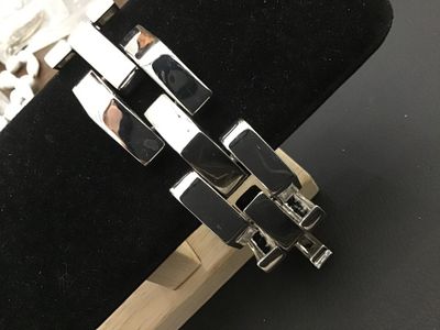 Sale Photo Thumbnail #122: Bold modern silver-tone wide link bracelet featuring stylized chevron/peak top panels with textured open undersides and a fold-over clasp. Features a small heart symbol stamped near the clasp. Bracelet measures approximately 7.5 to 8 inches in length and 