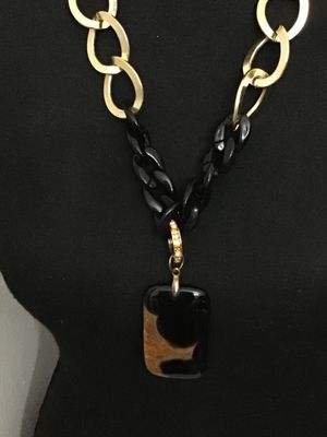 Sale Photo Thumbnail #135: Statement necklace by Traci Lynn featuring gold-tone open oval links combined with black curb links, completed with a toggle clasp closure marked TRACI LYNN. The necklace features a rectangular black and tortoise-shell style acrylic or stone pendant accen